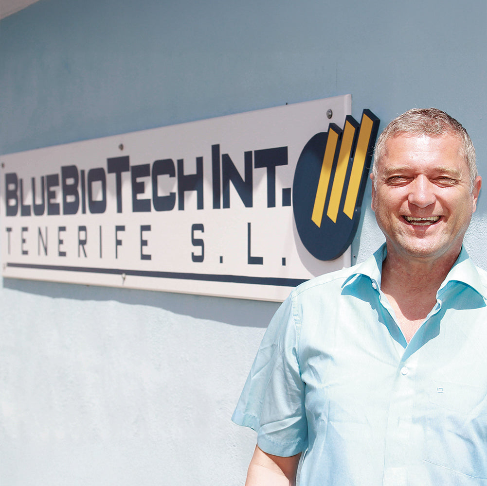 Dr. Peter Hartig lächelnd vor dem Firmenschild der BlueBioTech Int. Tenerife S.L., dem Zentrum seiner Algenkultivierung und Forschung.
